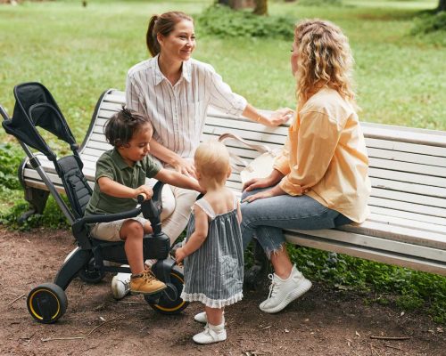 parents with infants talking on park bench